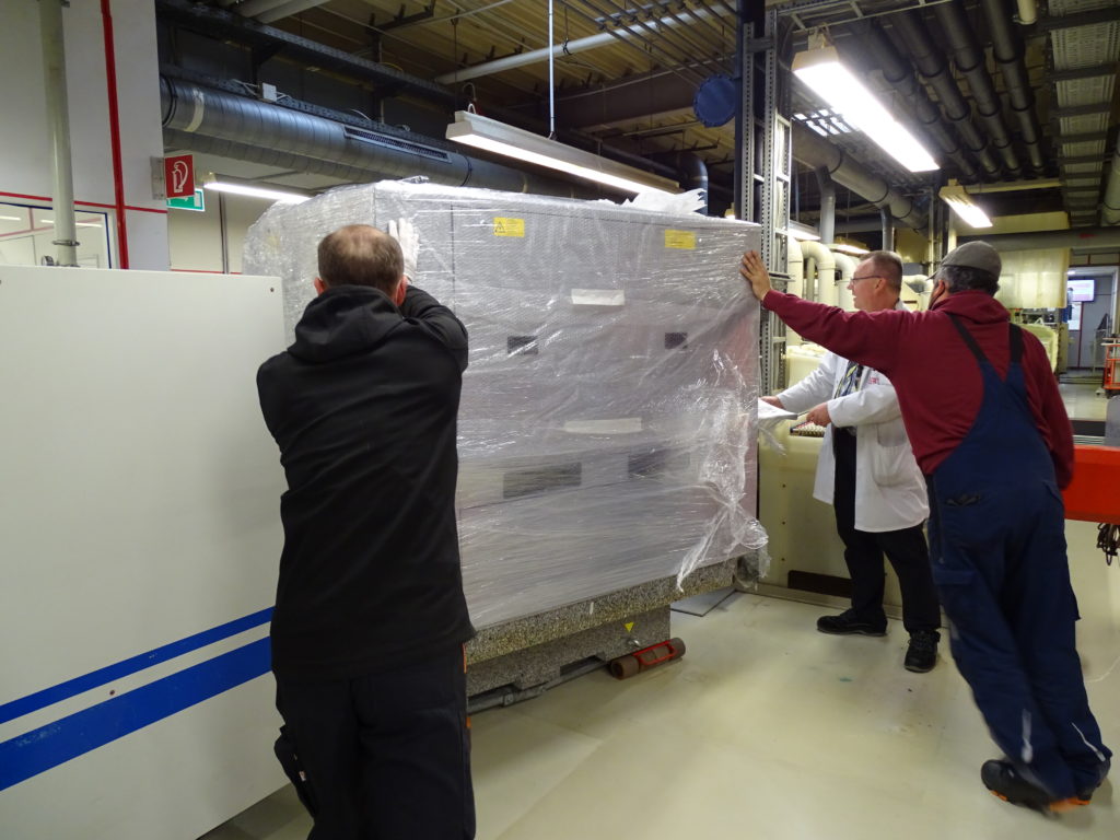3 Workers move measuring machine through production hall