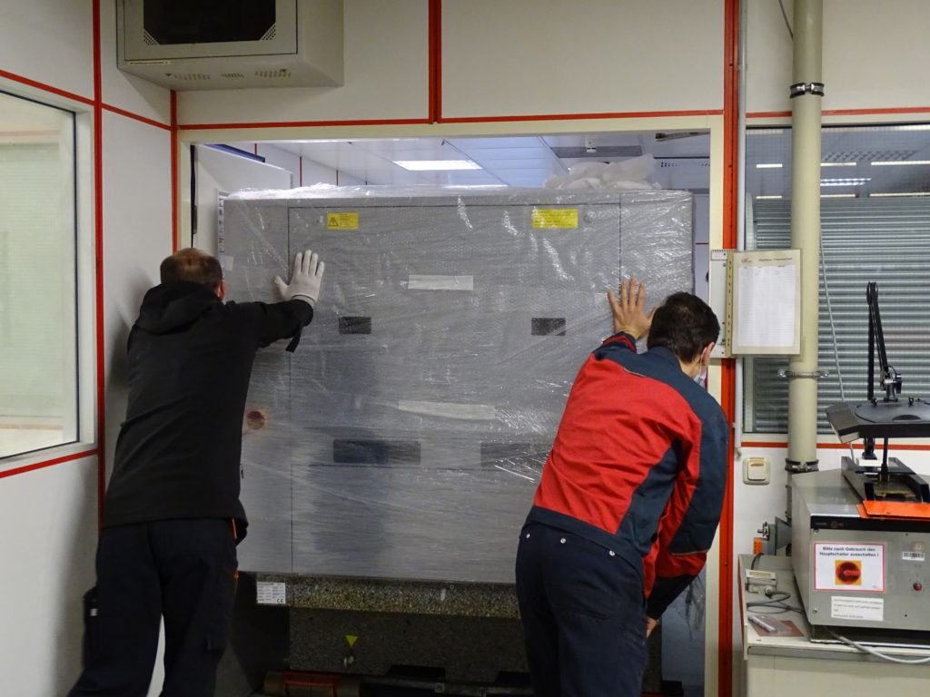 Two ILFA employees push measuring machine through the door